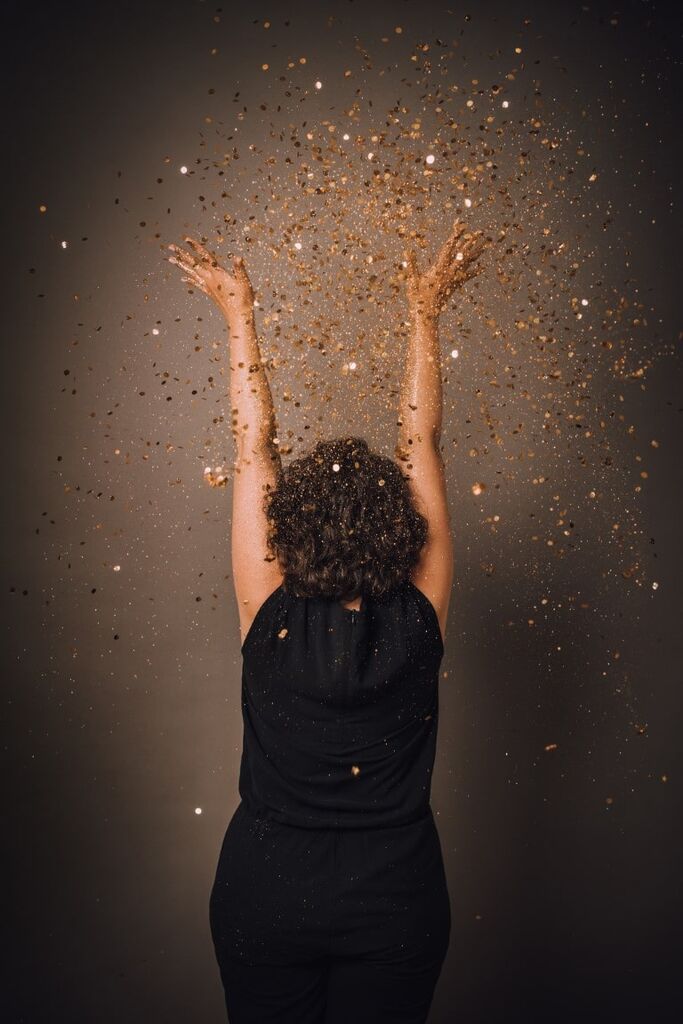 Bild von Frau, die Glitzerplättchen in die Luft wirft Bild von Frau, die Glitzerplättchen in die Luft wirft